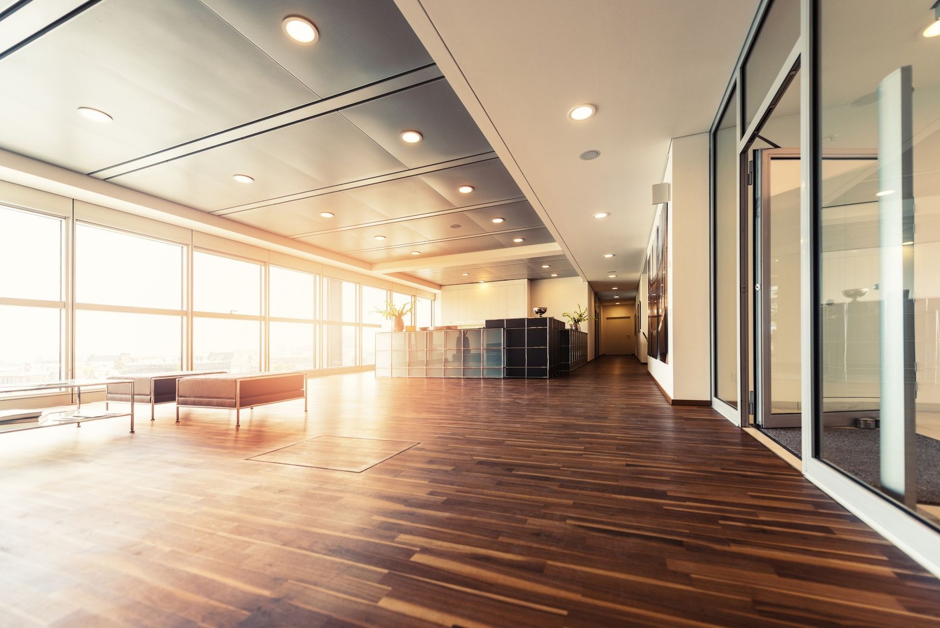 Sunlit business interior with a dark wood floor and glass partitions